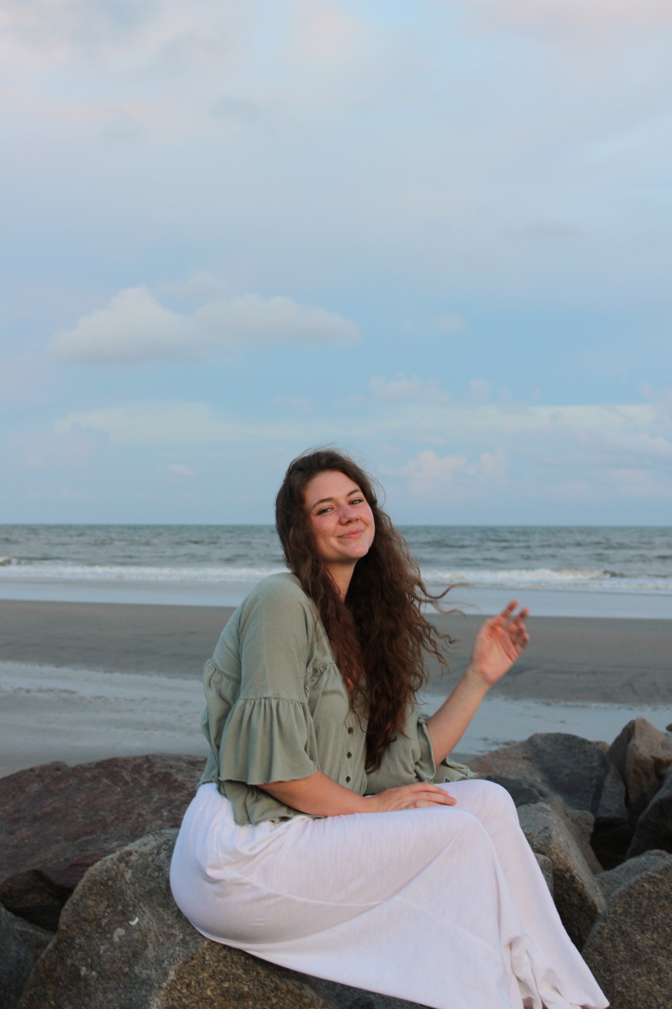 Sitting on rocks at the beach, looking back at camera