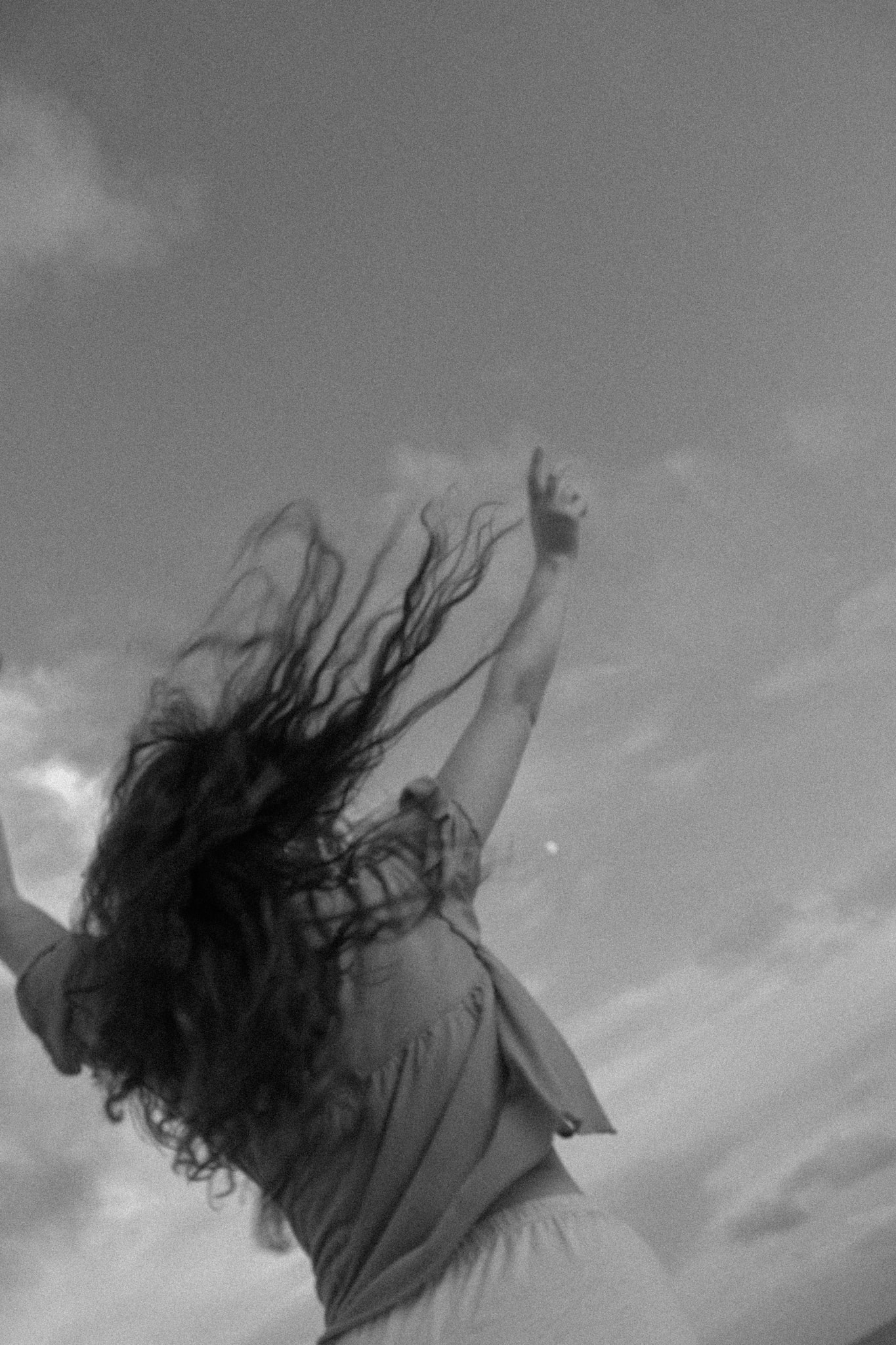 Black and white, arms raised to the sky, hair flying